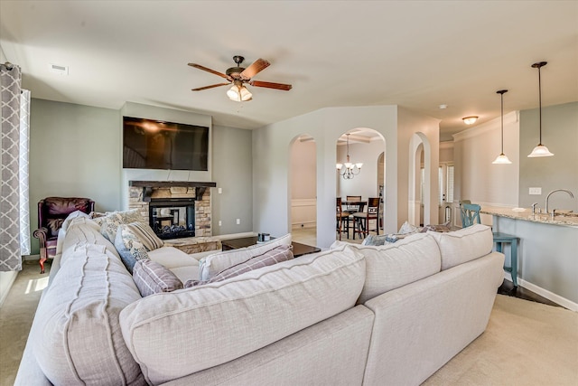 3374 Grove Landing Cir, Grovetown, GA 30813 - living room featuring arched walkways, a stone fireplace, a ceiling fan, and baseboards
