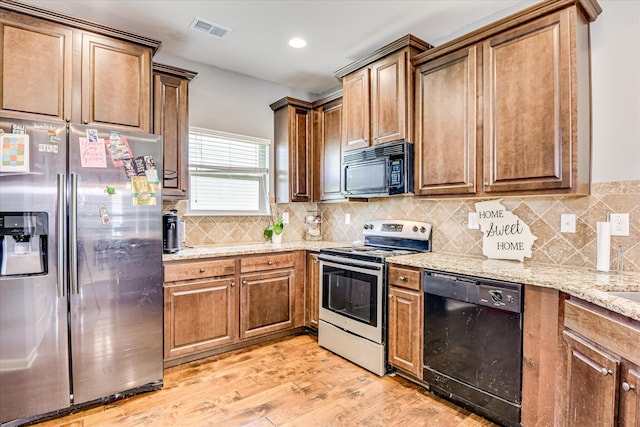3374 Grove Landing Cir, Grovetown, GA 30813 - kitchen featuring black appliances, light stone countertops, light wood-style floors, tasteful backsplash, and brown cabinets
