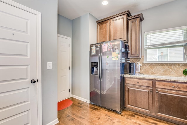 3374 Grove Landing Cir, Grovetown, GA 30813 - kitchen with stainless steel refrigerator with ice dispenser, light wood-style flooring, tasteful backsplash, baseboards, and light stone counters