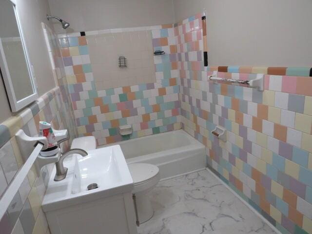 2810 Anne St, Augusta, GA 30906 - bathroom featuring vanity, washtub / shower combination, marble finish flooring, tile walls, and a wainscoted wall
