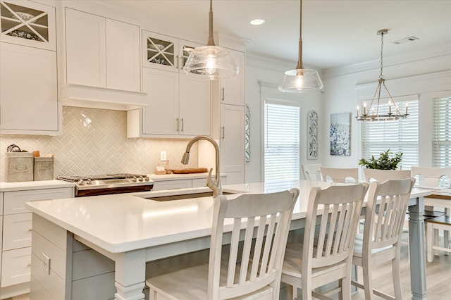 508 Oakley Grv Cir, Evans, GA 30809 - kitchen featuring stove, a kitchen island with sink, tasteful backsplash, light countertops, and crown molding
