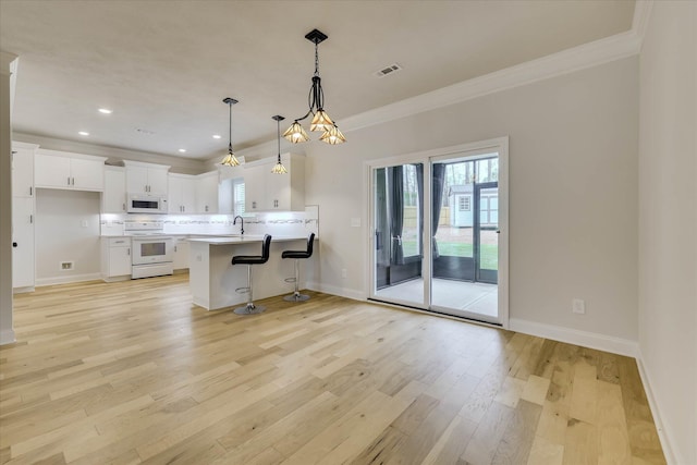 6135 Mottled Duck Dr, North Augusta, SC 29860 - kitchen featuring white appliances, crown molding, baseboards, a breakfast bar, and light wood-style flooring