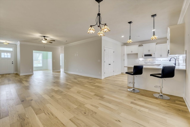 6135 Mottled Duck Dr, North Augusta, SC 29860 - kitchen with white microwave, light countertops, crown molding, light wood-style flooring, and a ceiling fan