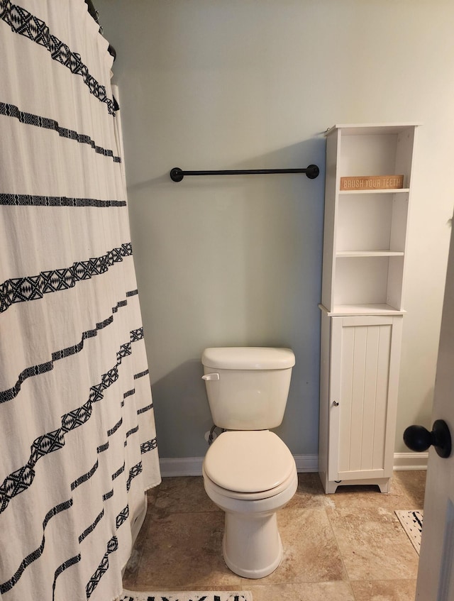 bathroom with curtained shower, toilet, and baseboards