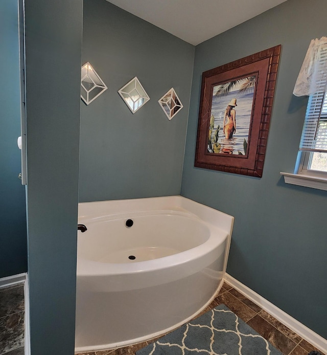 bathroom with a bath and baseboards