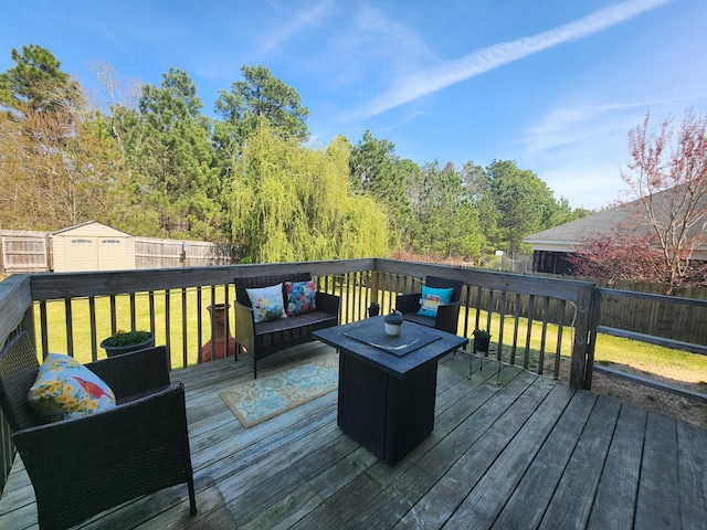 deck featuring a storage unit, an outdoor living space, a fenced backyard, a yard, and an outdoor structure