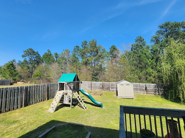 view of yard with a storage unit, an outbuilding, a fenced backyard, and a playground