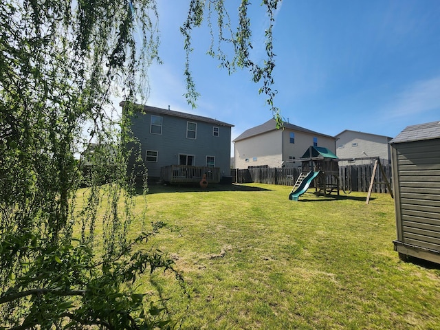 view of yard with a deck, a playground, and a fenced backyard