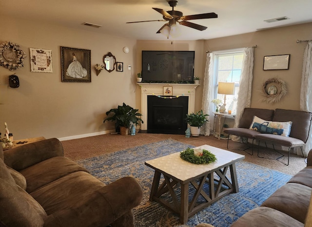 carpeted living area with ceiling fan, a fireplace, visible vents, and baseboards