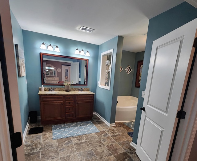 bathroom with double vanity, visible vents, baseboards, and a sink