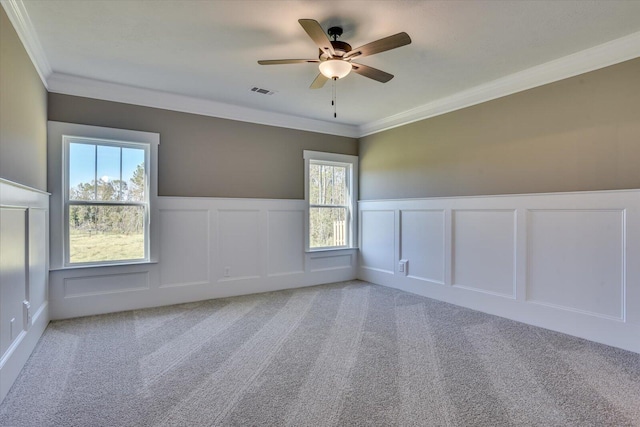 unfurnished room with ceiling fan, a healthy amount of sunlight, ornamental molding, and carpet floors