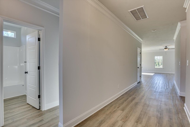 hall with light wood-type flooring and crown molding