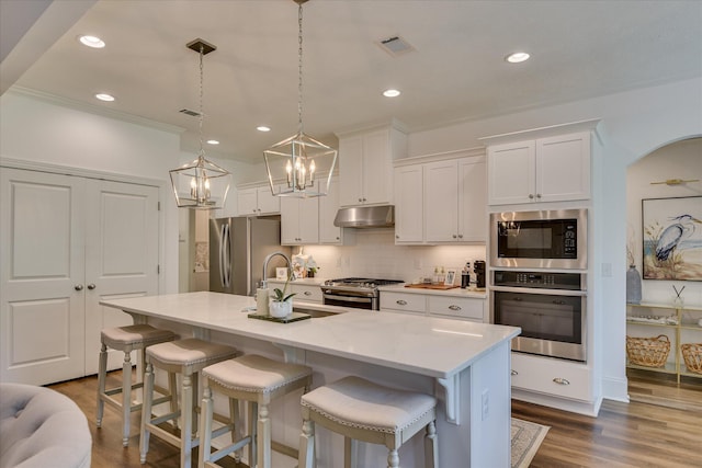 385 Bridle Path Rd, North Augusta, SC 29860 - kitchen with appliances with stainless steel finishes, under cabinet range hood, white cabinets, a chandelier, and a kitchen breakfast bar