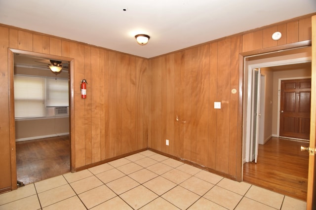 spare room with light wood-style floors, wooden walls, and a ceiling fan