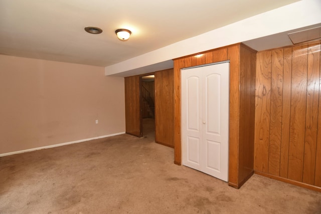 finished basement with light carpet, wood walls, and baseboards