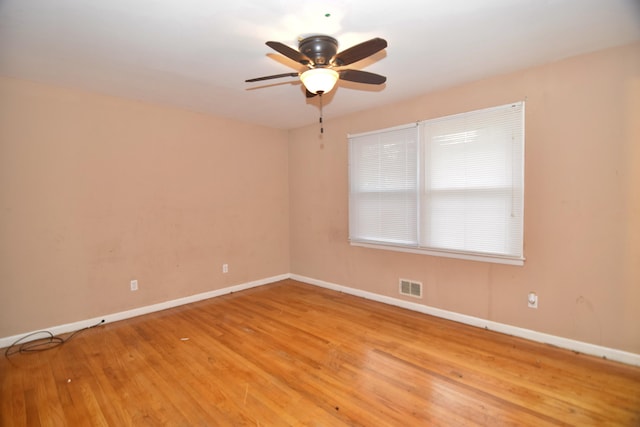 spare room featuring a ceiling fan, light wood-type flooring, visible vents, and baseboards