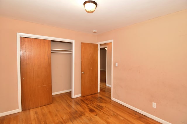 unfurnished bedroom featuring a closet, wood finished floors, and baseboards