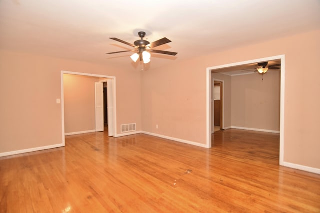 empty room with light wood-style floors, visible vents, baseboards, and a ceiling fan