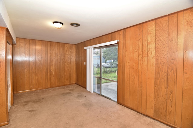 carpeted spare room featuring wooden walls