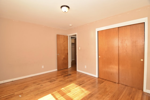 unfurnished bedroom featuring light wood-style floors, a closet, and baseboards