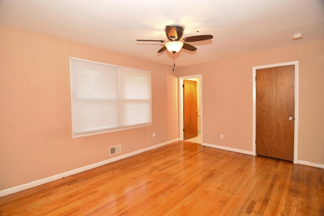 unfurnished bedroom featuring a ceiling fan, baseboards, visible vents, and wood finished floors