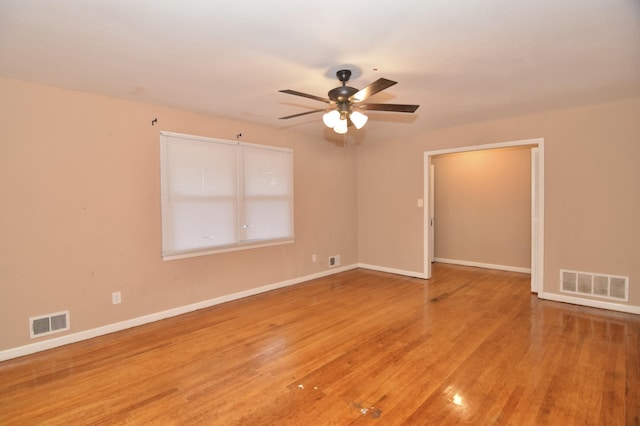 spare room with a ceiling fan, wood finished floors, visible vents, and baseboards