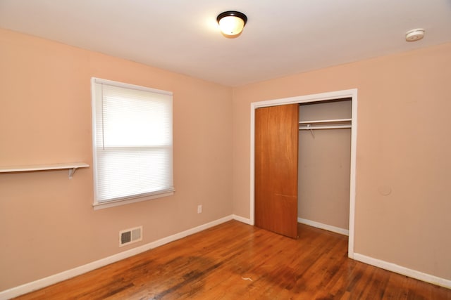 unfurnished bedroom with visible vents, baseboards, and wood finished floors