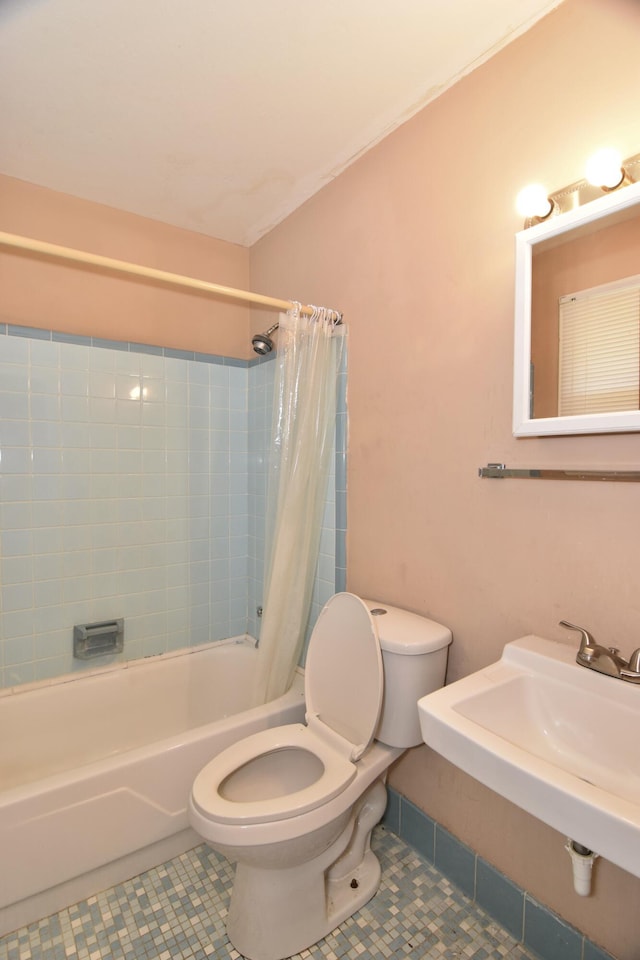 full bath featuring a sink, shower / bath combo with shower curtain, toilet, and tile patterned floors