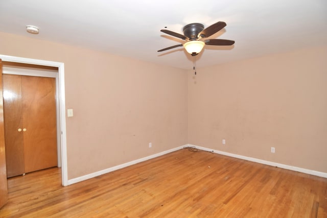 spare room with a ceiling fan, light wood-style flooring, and baseboards