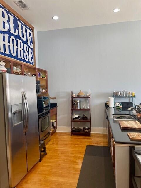 kitchen featuring stainless steel fridge with ice dispenser, stove, sink, and light wood-type flooring