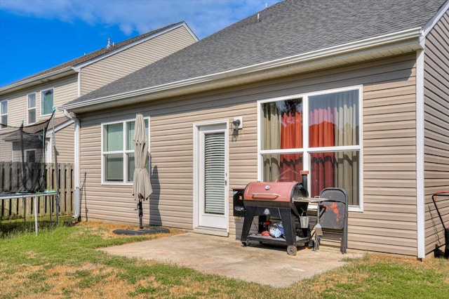 back of property with a lawn, a patio area, and a trampoline