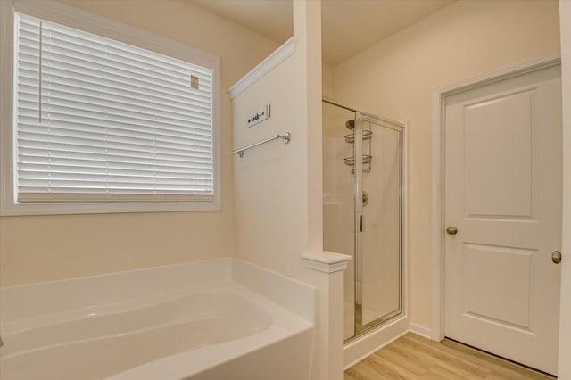 bathroom with wood-type flooring and shower with separate bathtub