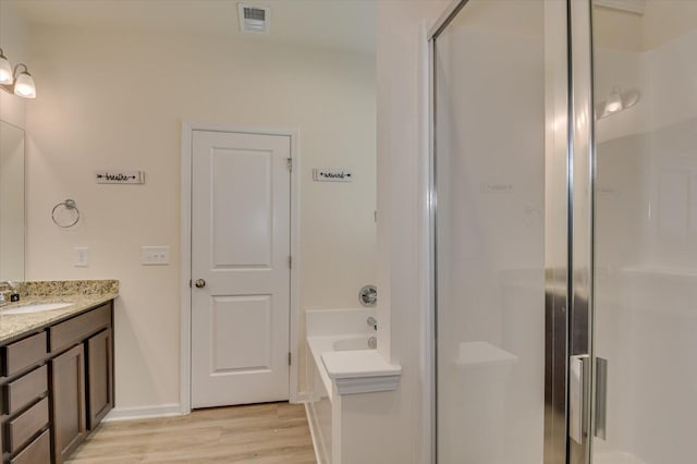 bathroom with walk in shower, vanity, and hardwood / wood-style flooring