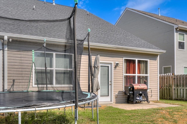 rear view of house featuring a trampoline, a patio, and a yard