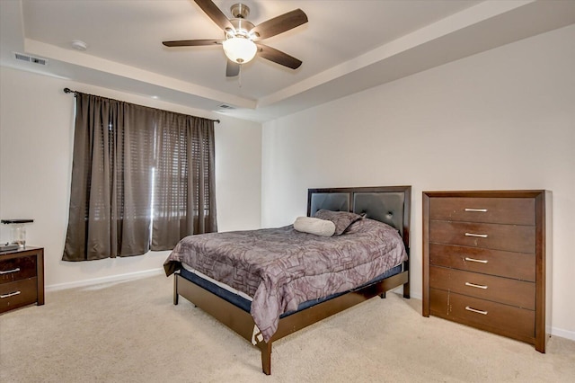 carpeted bedroom with a raised ceiling and ceiling fan