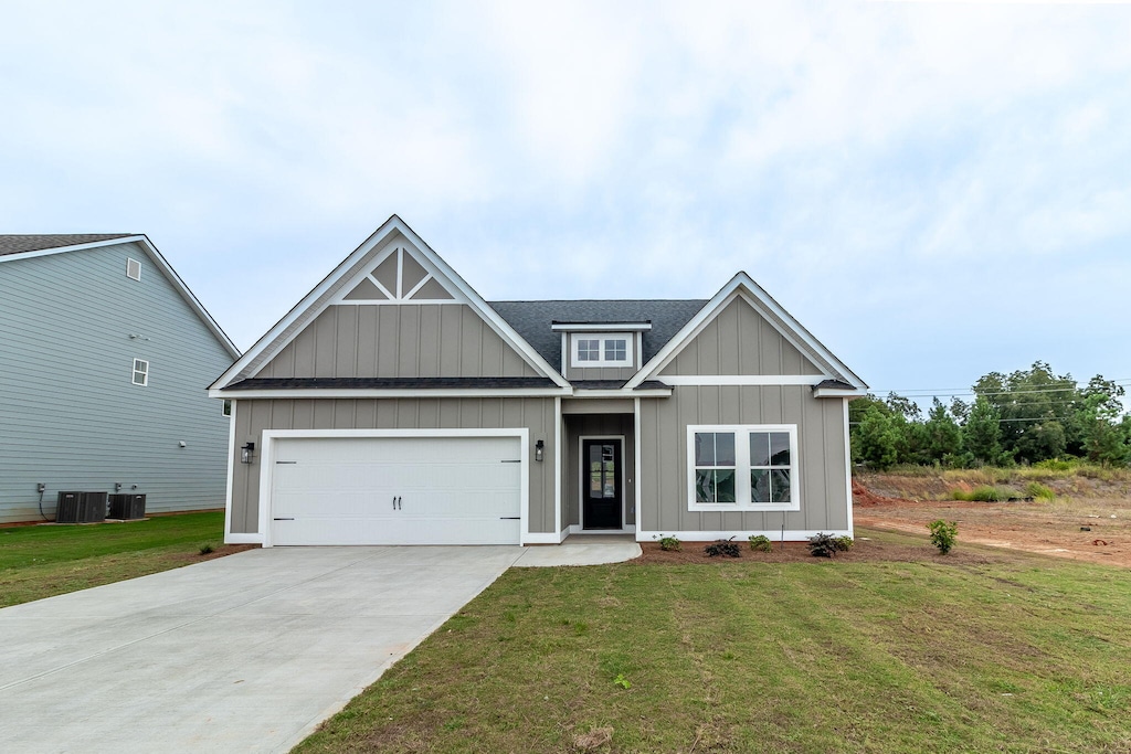 view of front of house with cooling unit, a garage, and a front lawn