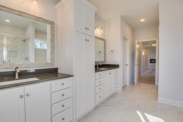 bathroom with walk in shower, ceiling fan, and vanity