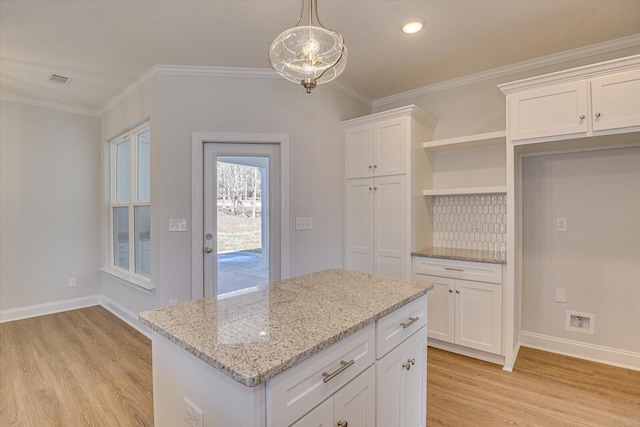 kitchen featuring white cabinetry, pendant lighting, crown molding, and light wood-type flooring