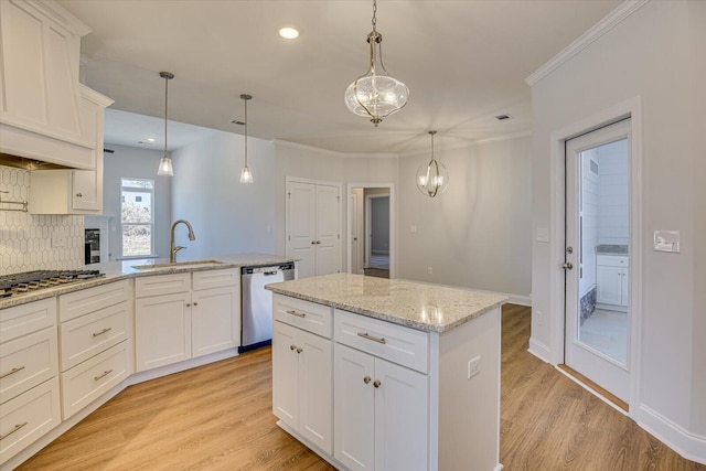 kitchen with sink, stainless steel appliances, a center island, light stone counters, and decorative light fixtures