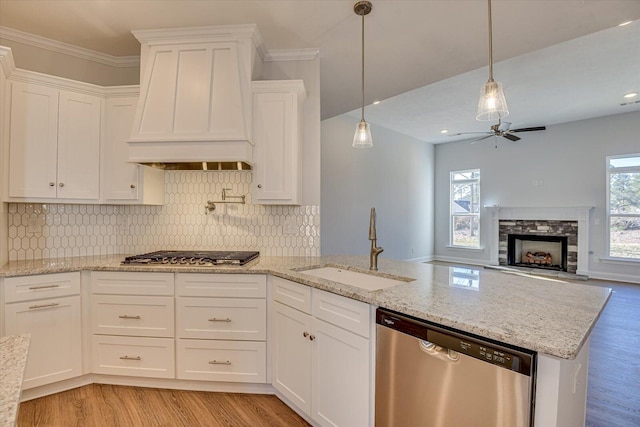 kitchen featuring sink, custom exhaust hood, pendant lighting, stainless steel appliances, and white cabinets