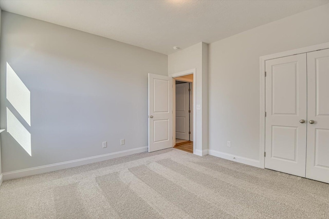 unfurnished bedroom featuring light colored carpet and a closet