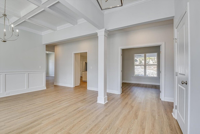 unfurnished living room with ornate columns, beamed ceiling, coffered ceiling, an inviting chandelier, and light hardwood / wood-style flooring