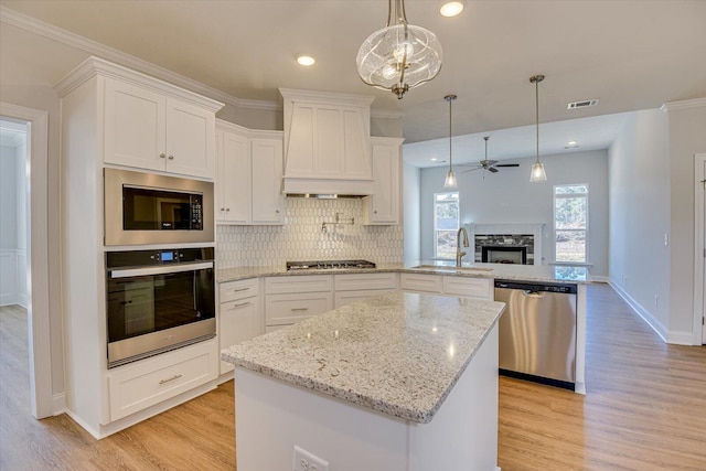 kitchen featuring appliances with stainless steel finishes, pendant lighting, white cabinets, kitchen peninsula, and custom range hood