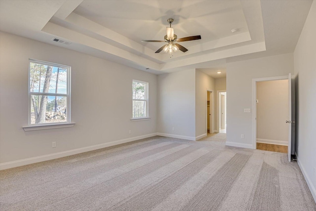 unfurnished bedroom with a tray ceiling, light colored carpet, and ceiling fan