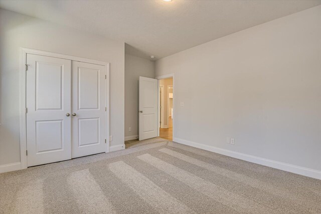 unfurnished bedroom featuring light colored carpet and a closet