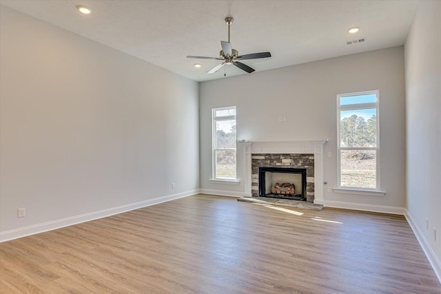 unfurnished living room featuring ceiling fan, a fireplace, and light hardwood / wood-style floors