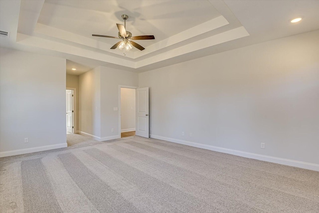 unfurnished room with light carpet, a tray ceiling, and ceiling fan