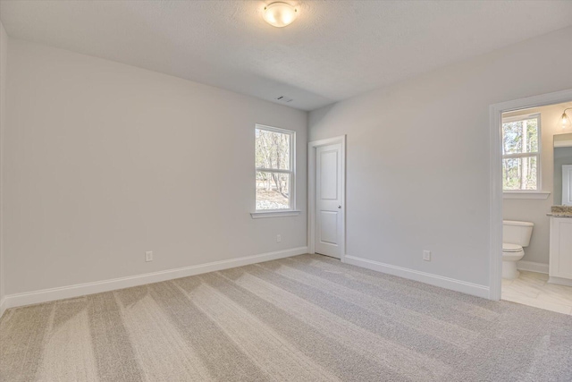 carpeted empty room with plenty of natural light and a textured ceiling