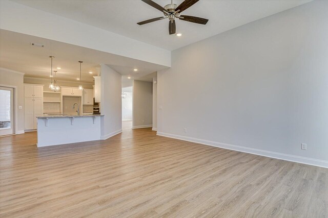 unfurnished living room featuring ceiling fan, sink, and light hardwood / wood-style floors