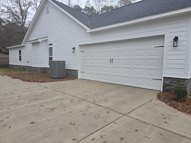 view of side of home featuring central AC unit and a garage